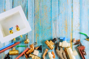 Plumbing tools and fixtures on a rustic wooden background, representing professional plumbing services in Minneapolis. Riser Water now offers expert plumbing in Minneapolis, including emergency plumber services for residential and commercial needs.